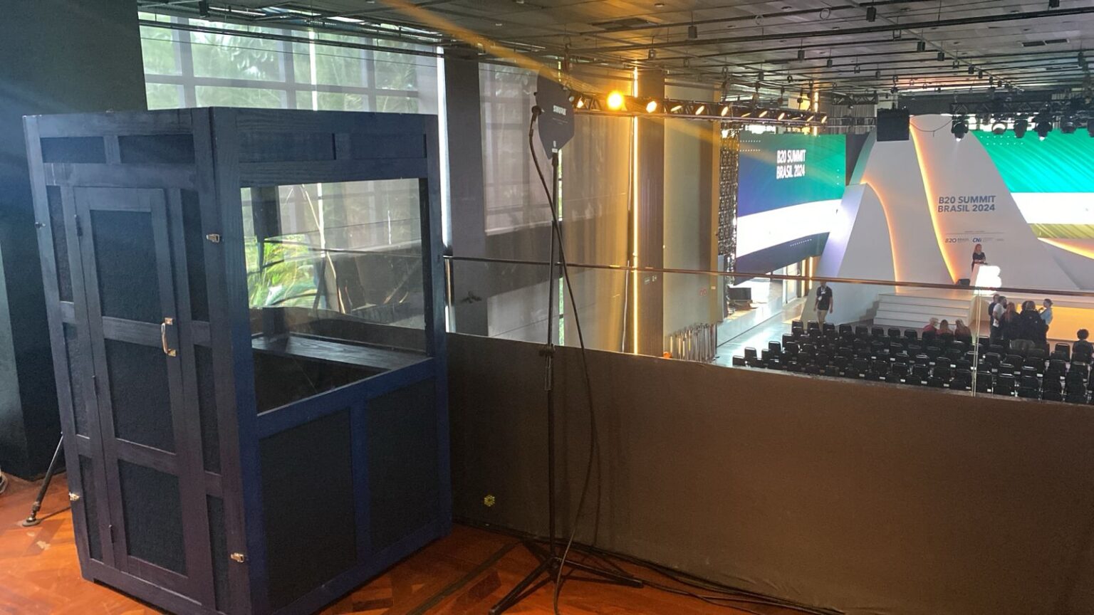 Cabine de narração para audiodescrição montada em evento, com equipamentos de transmissão para o público.