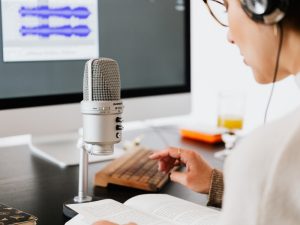 Guia de Equipamentos para Audiodescrição: O que é Essencial em Eventos e Produções - Está imagem é um close-up que captura uma pessoa envolvida na gravação de áudio, provavelmente em um contexto de produção de podcast, narração, ou, neste caso específico, audiodescrição.